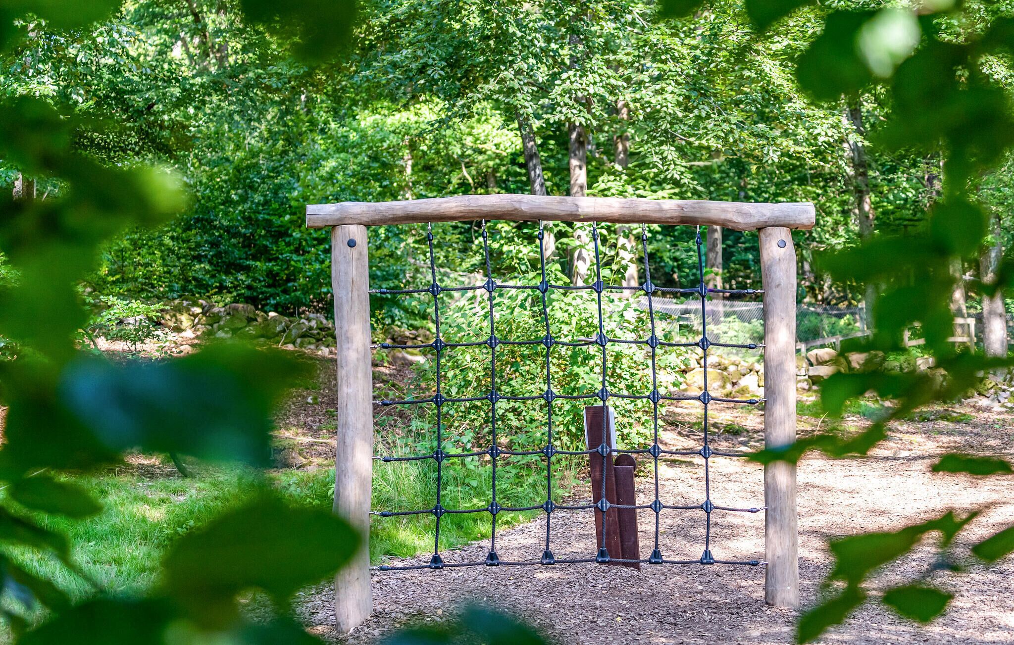 Une porte en bois avec une clôture en treillis métallique, située dans une zone boisée.