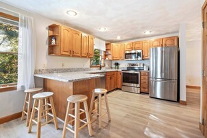 Una cocina moderna con armarios de madera, electrodomésticos de acero inoxidable y encimera de granito.