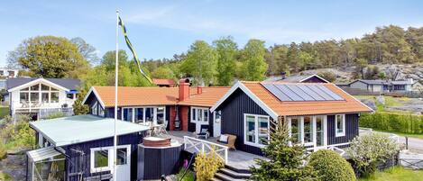A modern house with a large deck, a sauna, and solar panels.