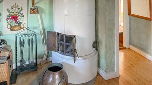 Ein Zimmer mit Kaminofen, Metalltopf und einer Wandtrocknerhalterung.