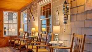 A cozy room with wooden furniture, including chairs and a table, and a window with a view. - Danemead Cottage - For 10ppl (Old Orchard Beach)