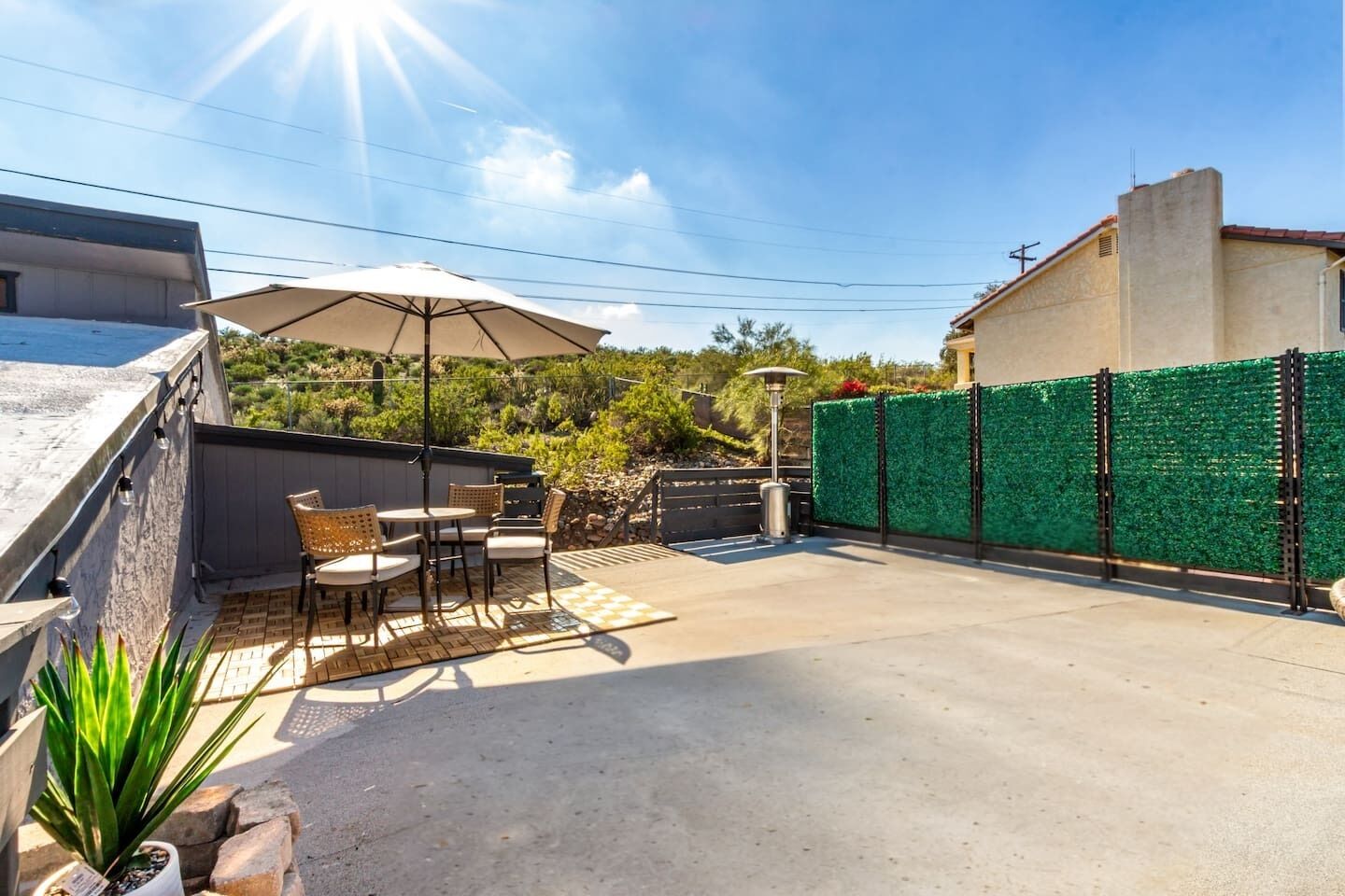 A patio area with outdoor furniture, a pergola, and a green fence.