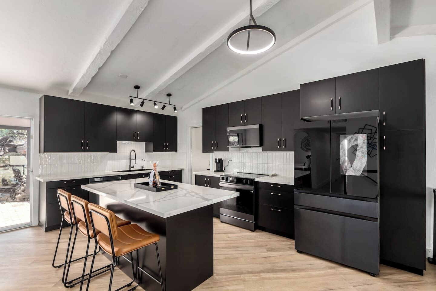 Une cuisine moderne avec des meubles de couleur noire, un îlot central et un grand réfrigérateur.