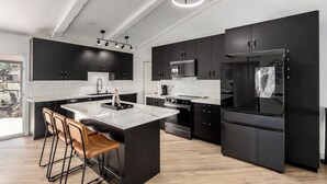 Una cucina moderna con mobili neri, un'isola centrale e un frigorifero grande.