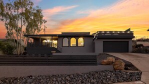 Una casa moderna con garage, area esterna coperta e vialetto con giardino roccioso.