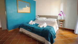 Una habitación de hotel con una cama, una mesita de noche, un jarrón con flores y un cuadro en la pared.