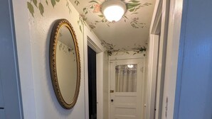 Ein Flur mit floralem Deckendesign, einem großen Spiegel und einem gemusterten Teppich.