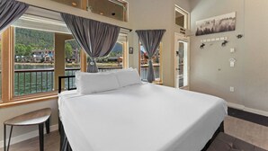 Ein Hotelzimmer mit einem großen Bett, Seeblick und einem Balkon mit Vorhängen.