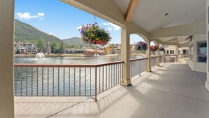 Ein überdachter Balkon mit Blick auf einen See und Gebäude im Hintergrund.