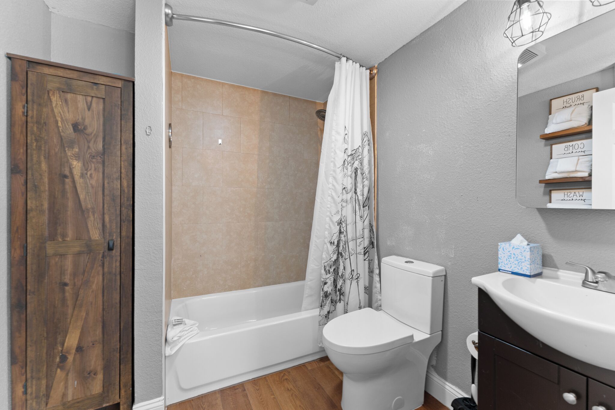 Une salle de bain avec une porte en bois, une baignoire, des toilettes et un lavabo.