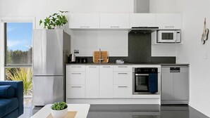A modern kitchen with white cabinets, a built-in oven, a microwave, and a coffee maker.