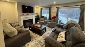 A cozy living room with a fireplace, sofas, and a television.