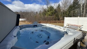 A hot tub with a clear view of the surrounding area, including trees and a building in the background.