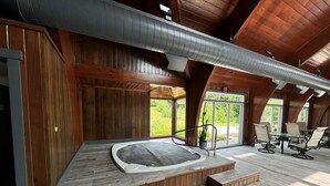A spa area with a hot tub, wooden flooring, and a view of greenery through large windows. - Greenspring towhhome- Free shuttle and clubhouse (Dover)