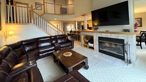 A spacious living room with a large leather sectional sofa, a fireplace, and a flat-screen TV mounted on the wall. - Greenspring towhhome- Free shuttle and clubhouse (Dover)