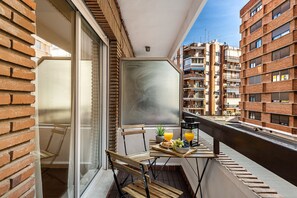 A balcony with a table set for breakfast, overlooking a cityscape with brick buildings. - Waou Sevilla Center V (Sevilla)