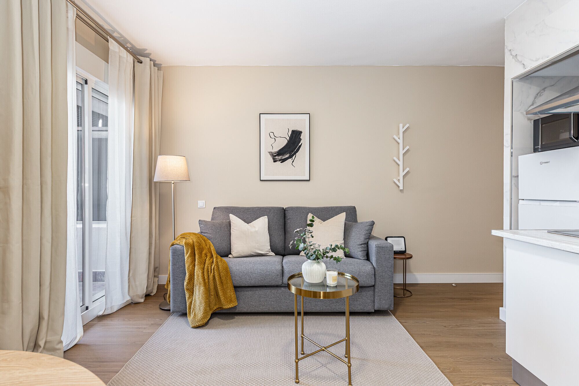 Een moderne woonkamer met een grijze bank, een klein rond tafeltje en een lamp.