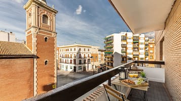 A balcony with a view of a historic tower and modern buildings.