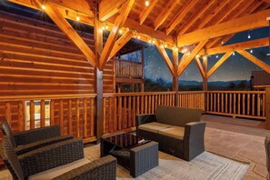 Une terrasse en bois avec mobilier d’extérieur, un balcon et une vue sur le ciel nocturne.