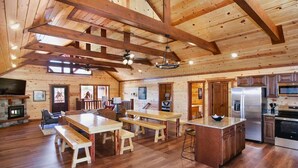 A spacious kitchen with wooden beams, a central island, and modern appliances. - Outdoor Theater + Jetted Hot Tub | 8BR Sleeps 24 (Sevierville)