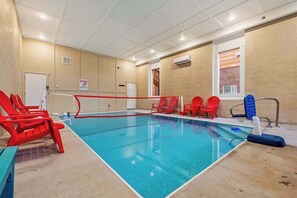 Une piscine intérieure équipée d’un filet de volley-ball, de chaises rouges et d’une planche de natation bleue.