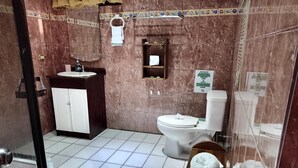 A bathroom with a sink, toilet, and a towel on the floor. - Family room 2 (Manuel Antonio)