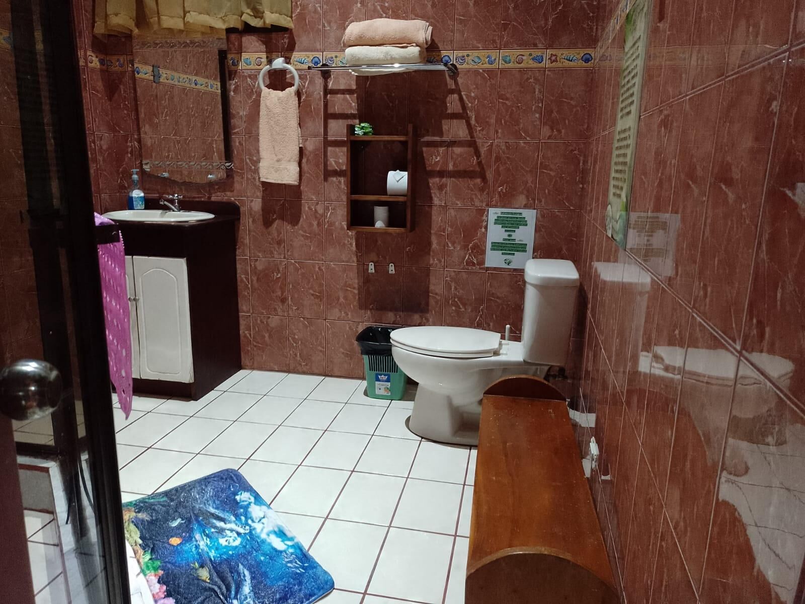 Un baño con lavamanos, inodoro y un banco de madera.