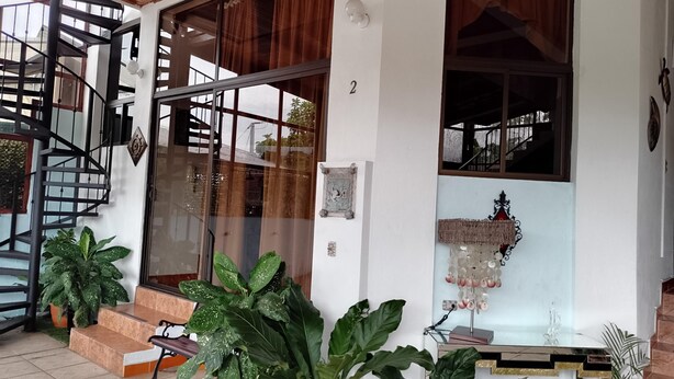 A modern house with a spiral staircase, large windows, and potted plants. - Family room 2 (Manuel Antonio)