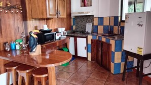 A compact kitchen with wooden cabinets, a microwave, a stove, and a refrigerator. - Family room 2 (Manuel Antonio)