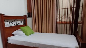 A single bed with a wooden headboard and a green pillow.