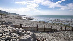 Una playa rocosa con una cerca de madera y un camino de madera que lleva al agua.