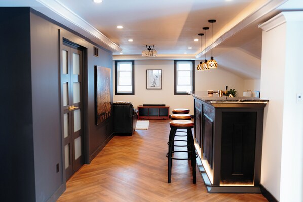 Uma cozinha moderna com piso de madeira, área de bar com banquetas e iluminação pendente.
