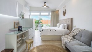 Un dormitorio moderno con cama, sofá, escritorio y balcón con vistas.