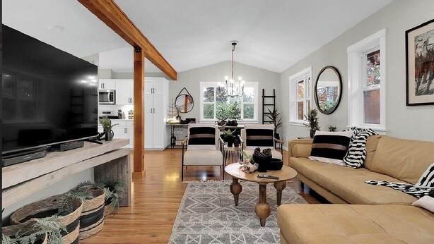 A modern living room with a TV, sofa, coffee table, and dining area.