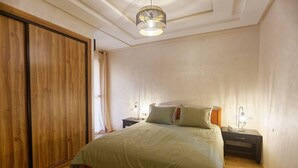 A bedroom with a bed, nightstands, a lamp, and a wardrobe. - Marrakech 2 Bedroom Brown Luxury Apartment (Marrakech)