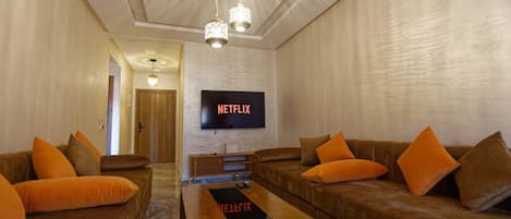 Una sala de estar con dos sofás marrones, una mesa de centro de madera y un televisor montado en la pared.