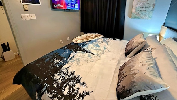 Una camera da letto con un letto, una TV a schermo piatto montata a parete, una ventola a soffitto e una citazione motivazionale sulla parete.