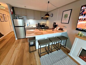 Une cuisine moderne dotée d’un îlot central, de tabourets de bar, d’un four à micro-ondes et d’une cuisinière.