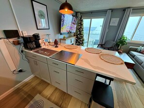 A modern kitchen with a large island, a coffee machine, and a TV mounted on the wall.