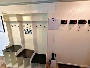 A room with a white wall, a black bench, and a whiteboard with hooks.