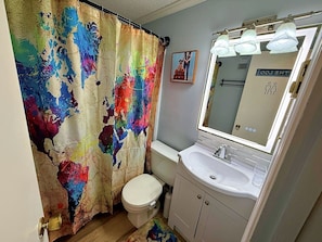 Une salle de bain avec des toilettes blanches, un lavabo et un miroir.