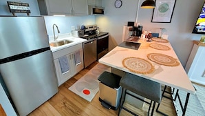 Una cucina moderna con elettrodomestici in acciaio inox, un'isola centrale e una sveglia appesa al muro.
