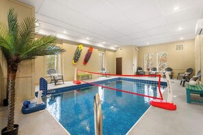 Ein Hallenbad mit Netz, Stühlen und einer Palme.