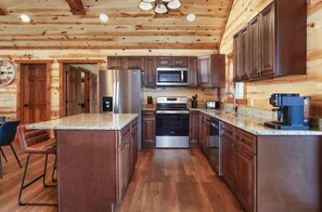 Eine Küche mit Holzausstattung, Edelstahlgeräten und einer Arbeitsplatte aus Granit.