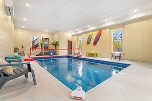 En inomhuspool med ett rött säkerhetsnät, ett litet bord och en stol.