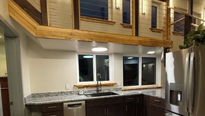Una cocina moderna con armarios de madera oscura, un refrigerador de acero inoxidable y una encimera de granito.