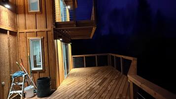 A wooden deck with railings, a ladder, and a bucket, likely for maintenance.