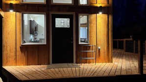 Una cabaña de madera con un porche, ventanas amplias y una puerta.