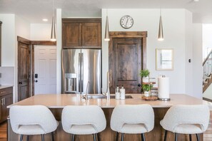 A kitchen with a central island, stainless steel appliances, wooden cabinets, and a hanging light fixture. - Summer by the Lake! Beautiful Swimming Pool, Patio w Hot Tub and BBQ Nature Trails Hiking Biking (Hideout)
