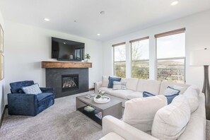 A living room with a fireplace, a sofa, a coffee table, and a television. - Summer by the Lake! Beautiful Swimming Pool, Patio w Hot Tub and BBQ Nature Trails Hiking Biking (Hideout)